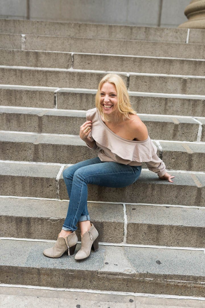 slouchy off the shoulder sweatshirt and booties with jeans on sidewalk in NYC.