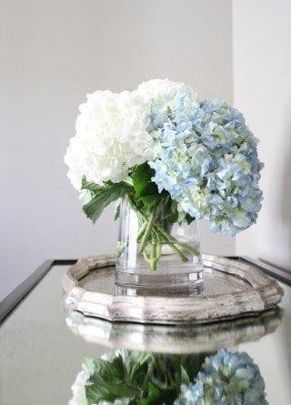 White and blue hydrangeas on mirrored consoled table with silver tray.