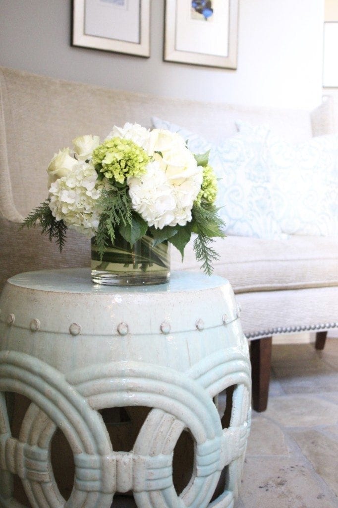 Mint green double coin garden stool for foyer entry table. Decorated with white hydrangea bouquet. 