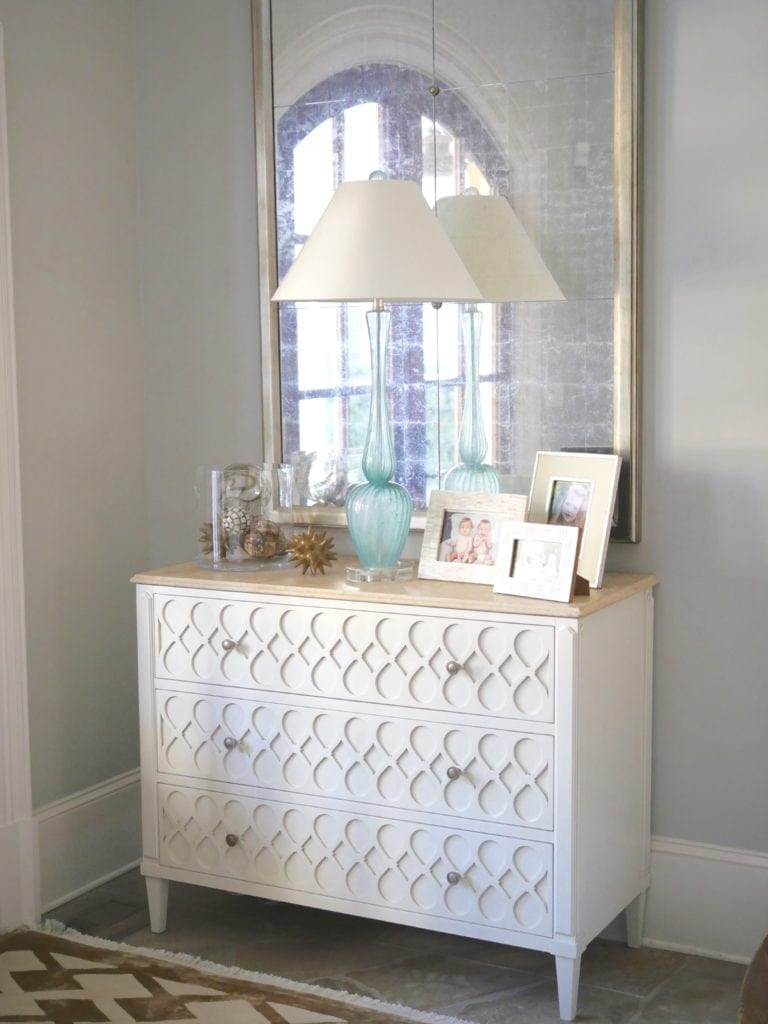 Foyer entry table with turquoise lamp. Light wood console with gold distressed mirror and light colored accents. Brushed Aluminum paint color.