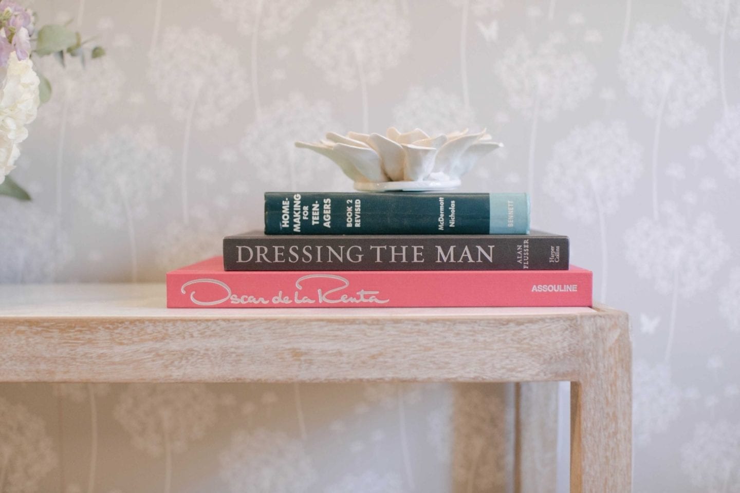 NuWallpaper WallPops gray wallpaper. pink oscar de la rents coffee table book stacked with other coffee table books on a console