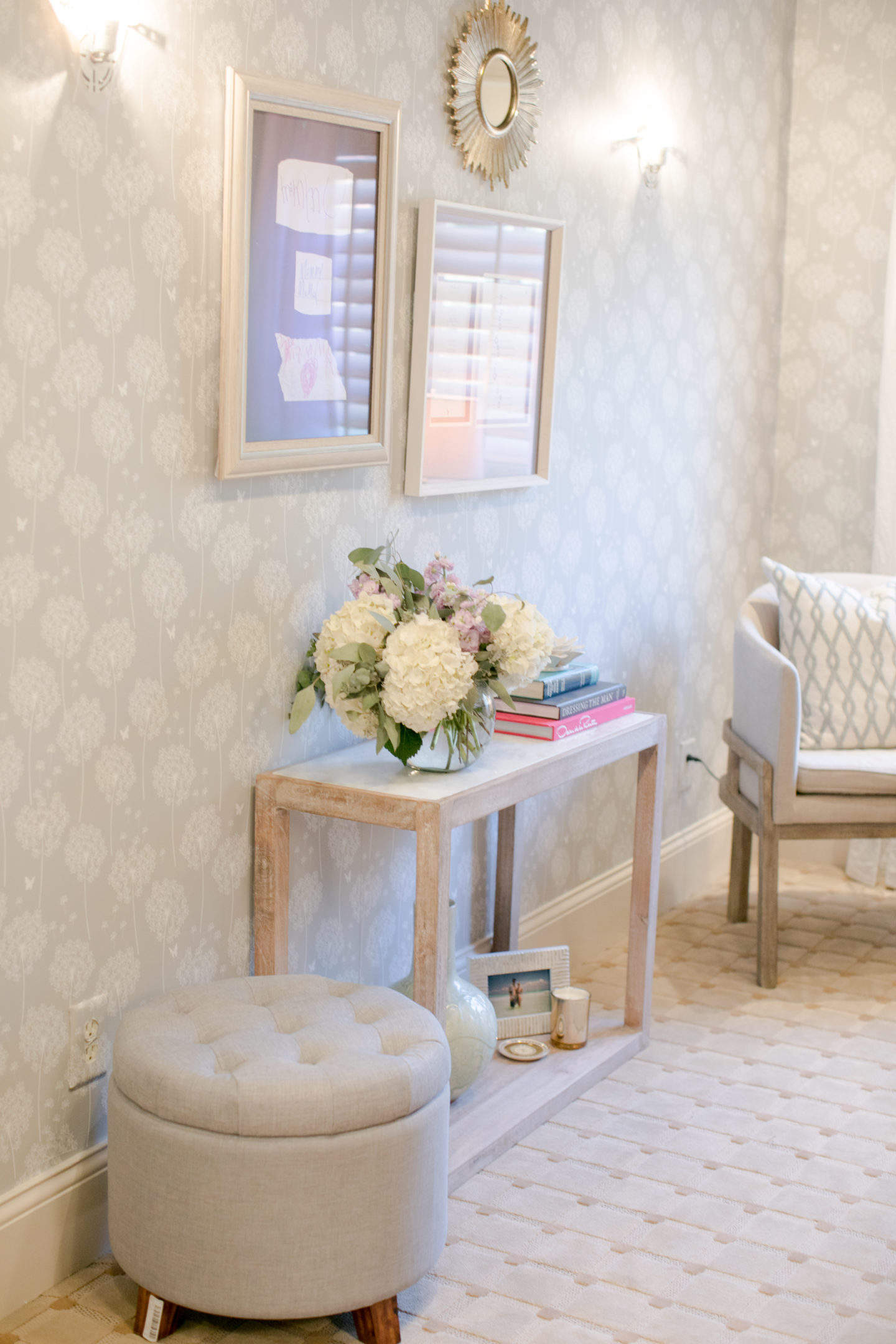 This home office with peal and stick taupe floral wallpaper has a white marble and washed wood console in light gray with a hidden storage furniture piece from Target.
