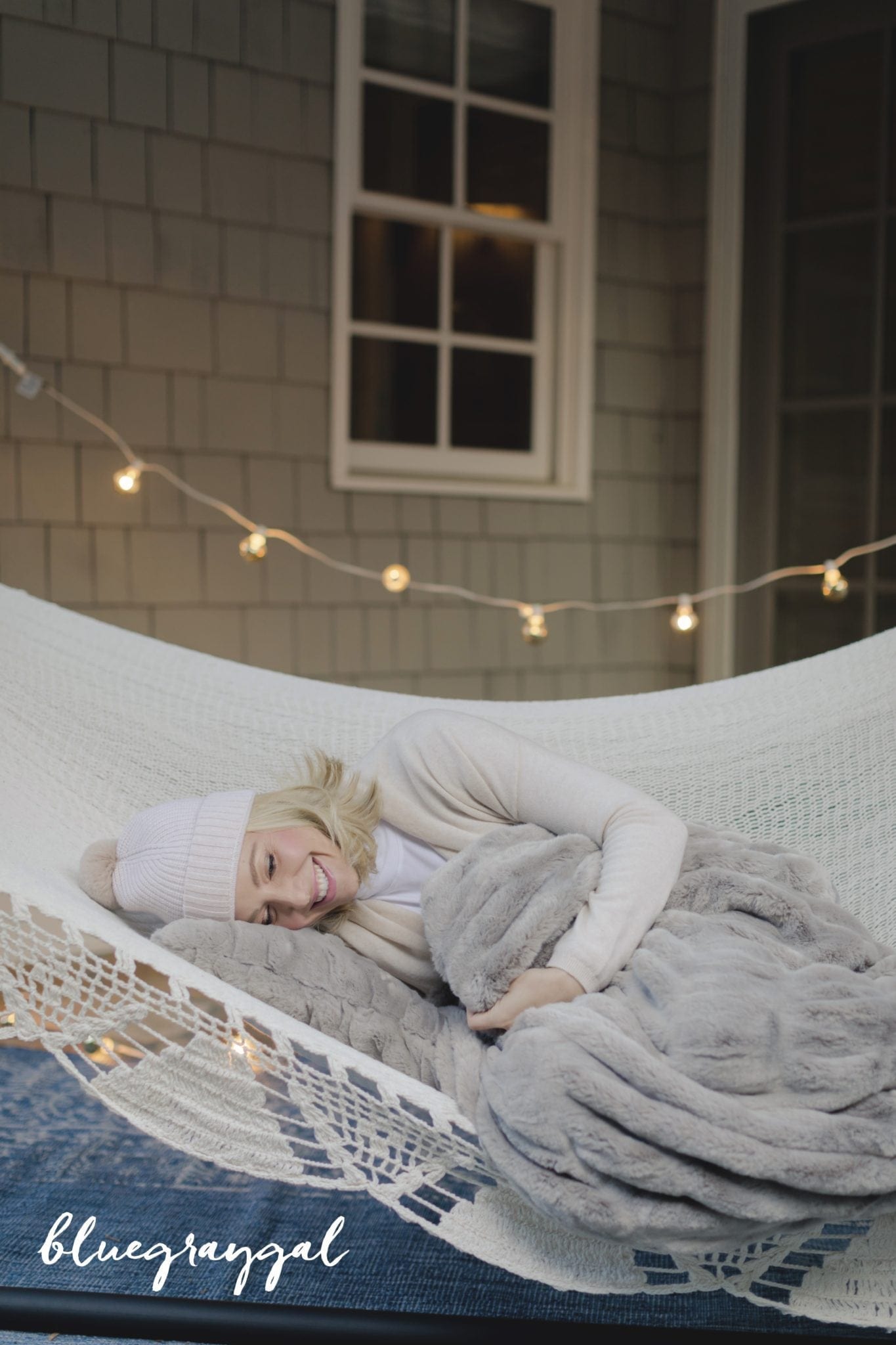 faux fur throw blanket from pottery barn with kelly page laying in woven hammock and lights hanging outside house