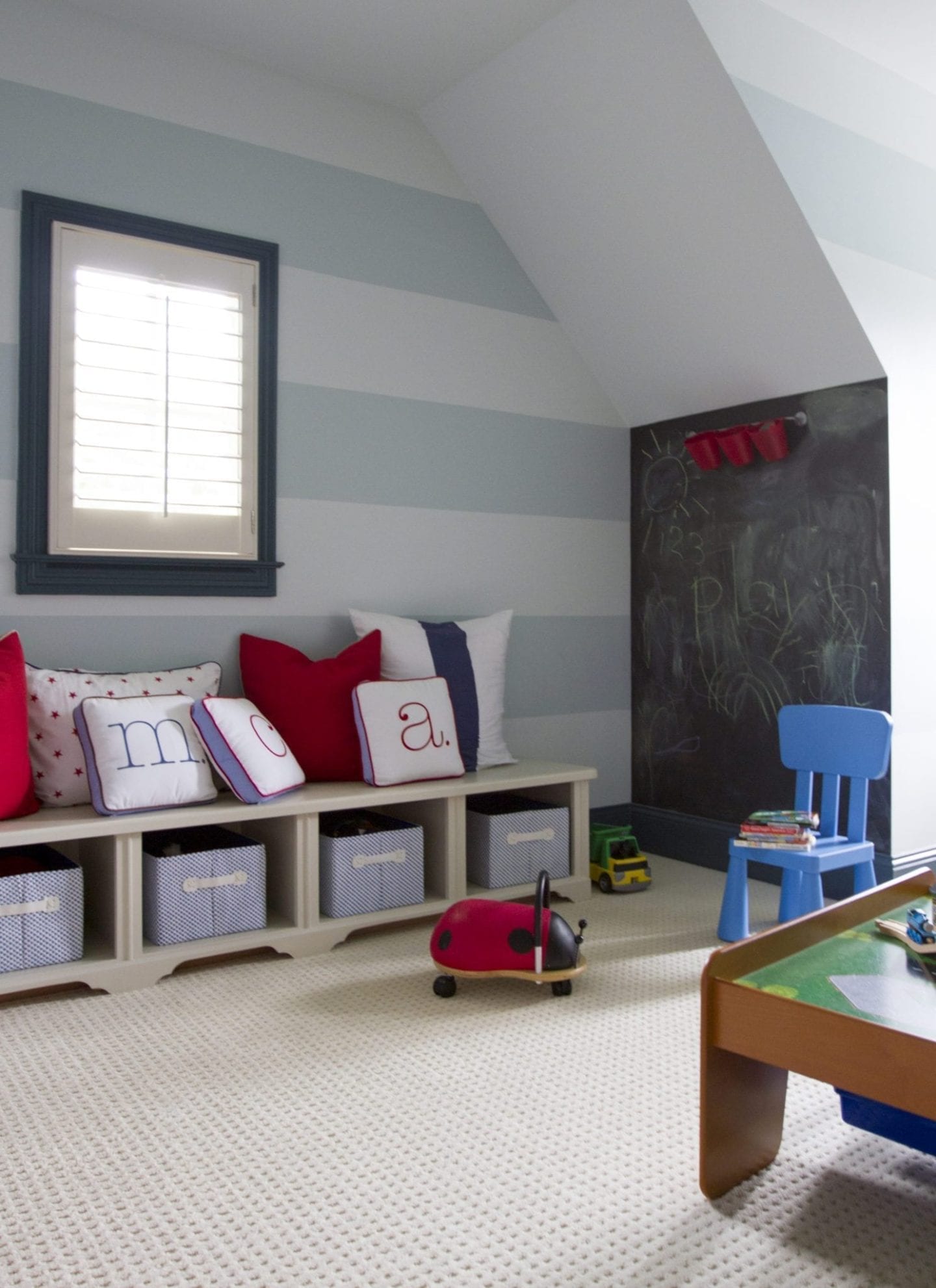 Kids playroom with cabana stripes and chalkboard wall with red blue and white pillows.