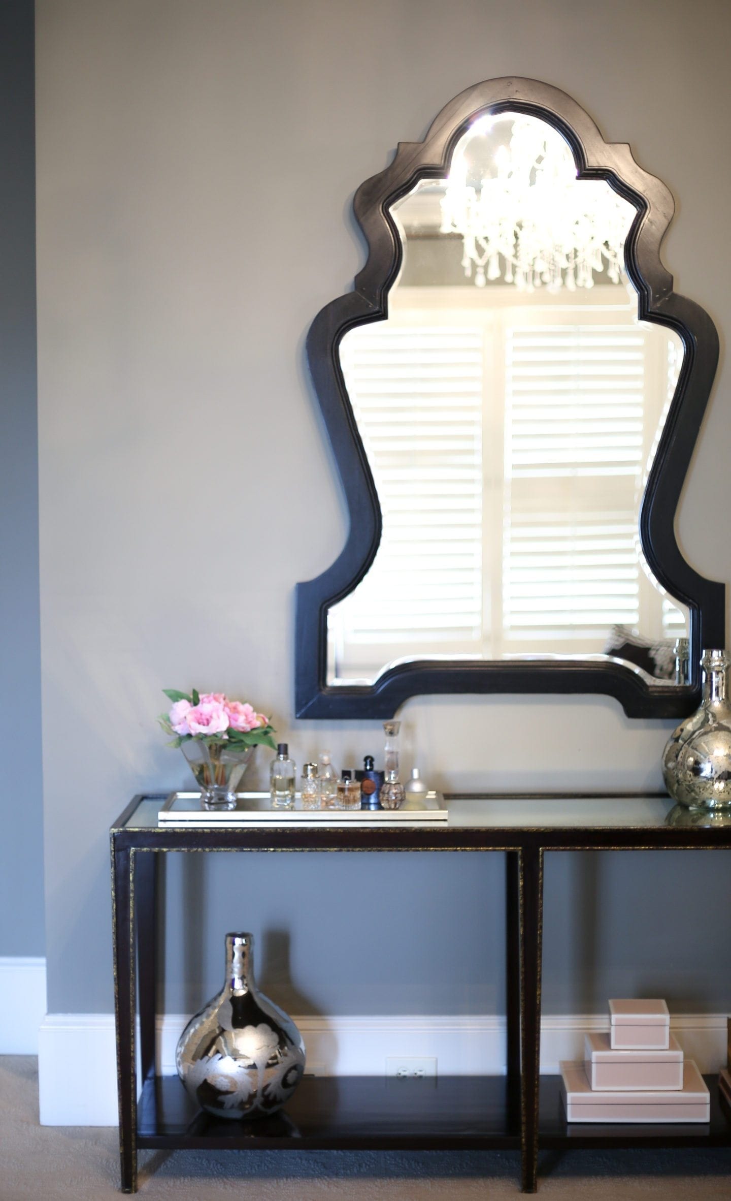 Benjamin Moore dark gray paint on the walls of a bedroom decorated in gray, gold and black. Oversized large black framed mirror. 