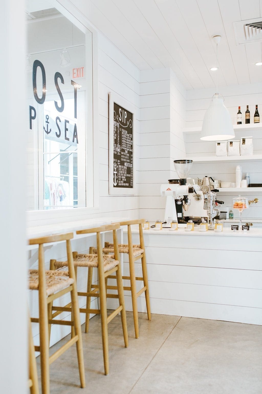 The Outpost Coffee Shop in Rosemary Beach. All white shiplap design coffee shop. This bright and happy coffee shop has character and fun. I love the design of the white bar counter and all white shelving with white lighting.