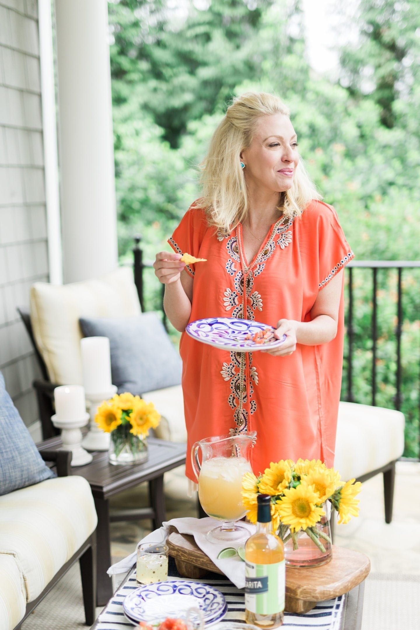 Cindo de Mayo patio party with coral bathing suit cover up and yellow sunflowers on blue and white table setting.