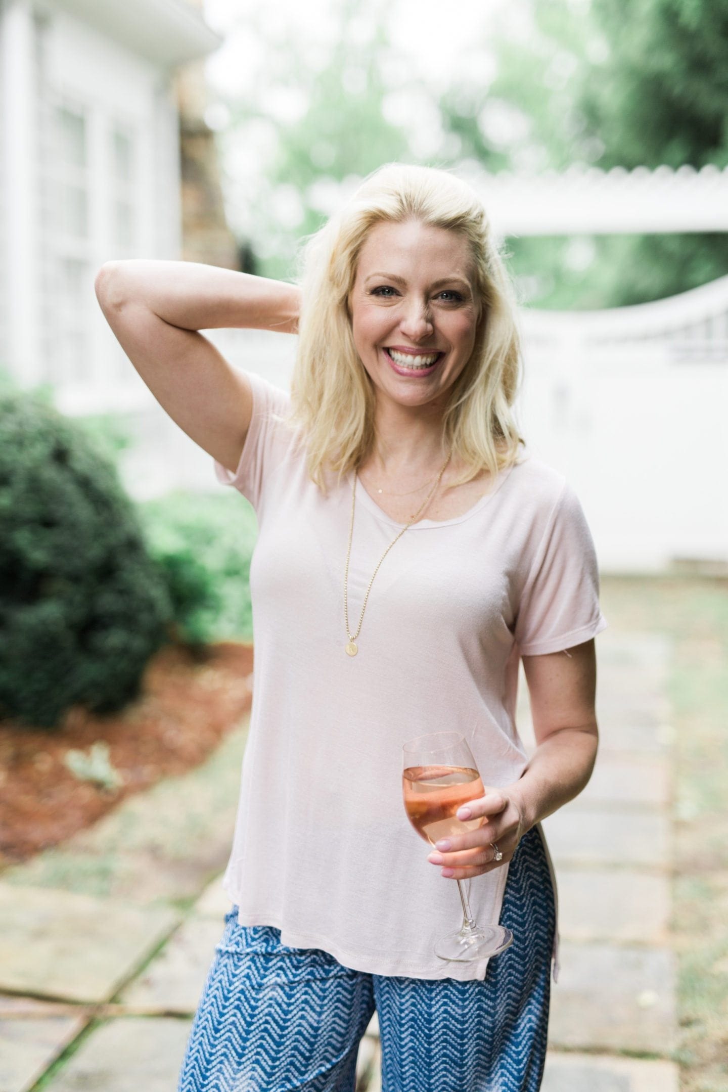 Light pink tee shirt and long gold necklace with charm. Casual outfit for women. 