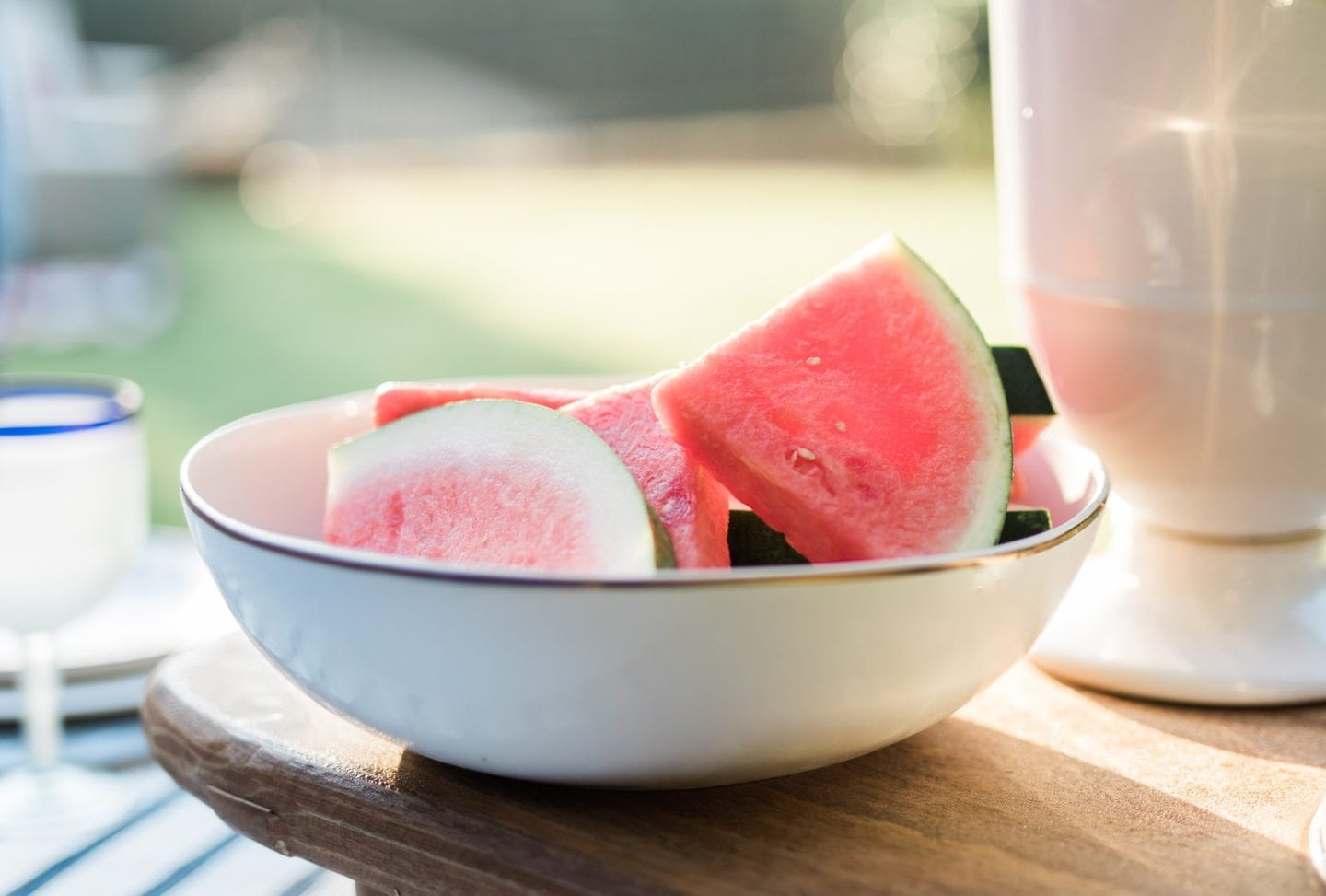 Sliced watermelon in white bowl with gold rim.
