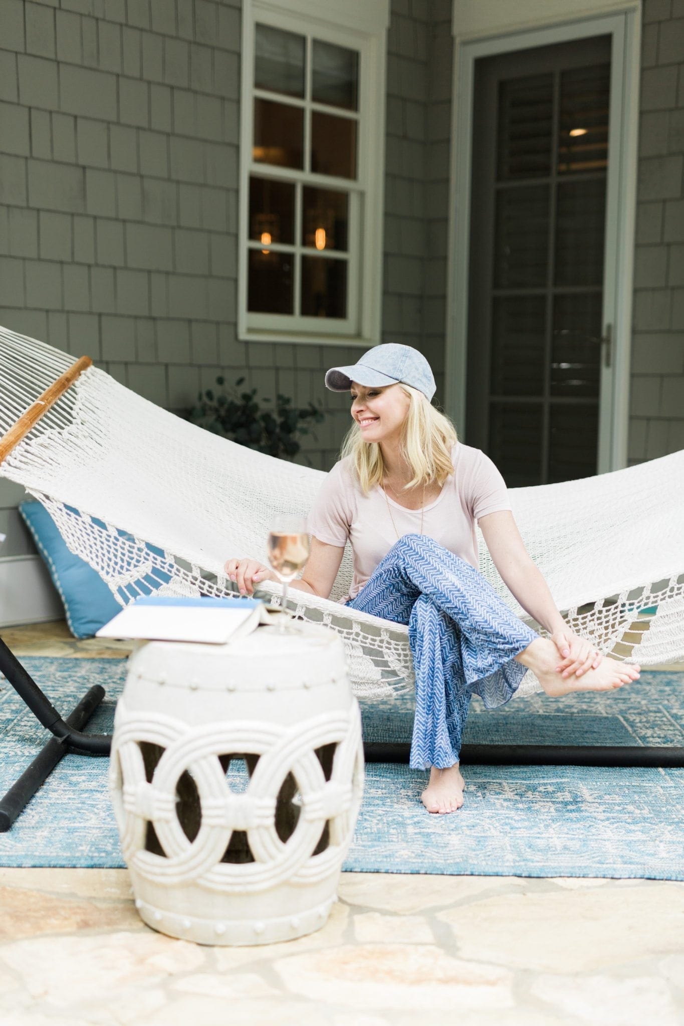 Home blogger Kelly Page in outdoor pretty hammock with garden stool.