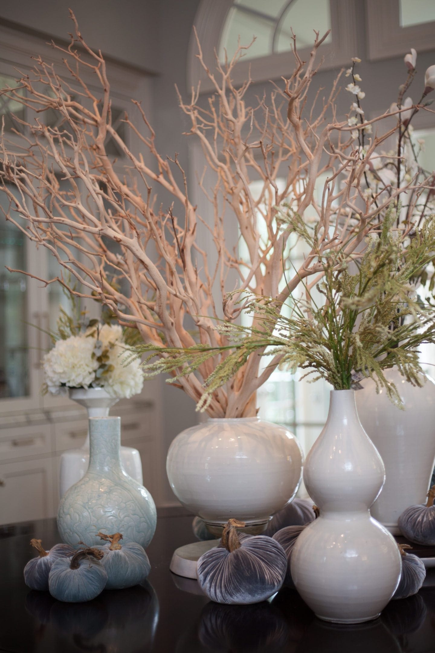 Silk floral arrangements in white urns. Beautiful clean white centerpiece with manzanita branches for a round dining room table.