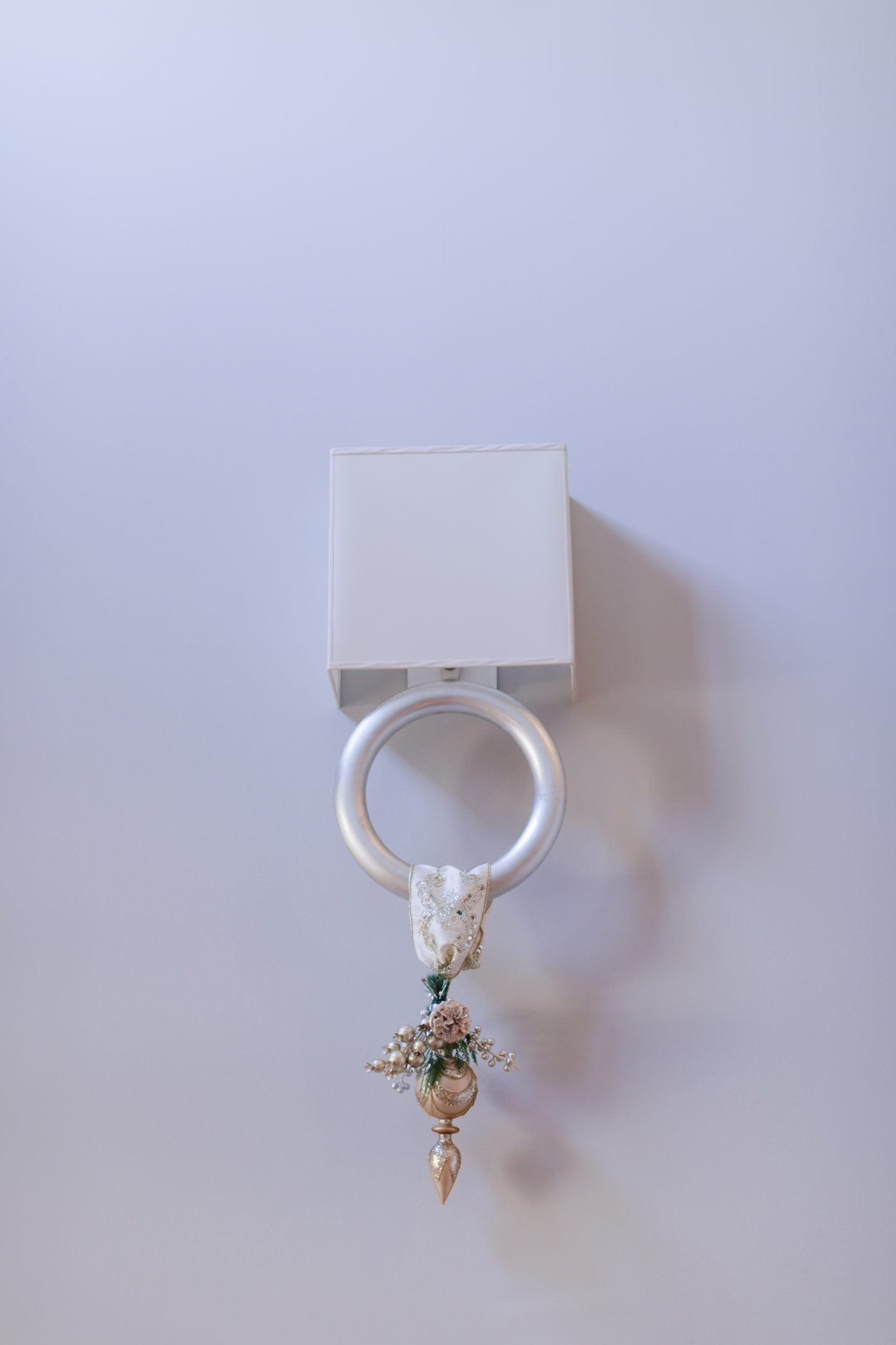 Ornament hanging from light fixture. Silver sconce with shade. 