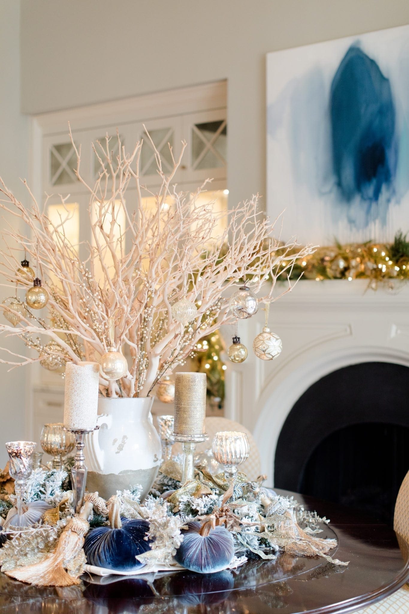 Christmas centerpiece idea. Manzanita branch centerpiece with ornaments hanging from them on a round dinner table.