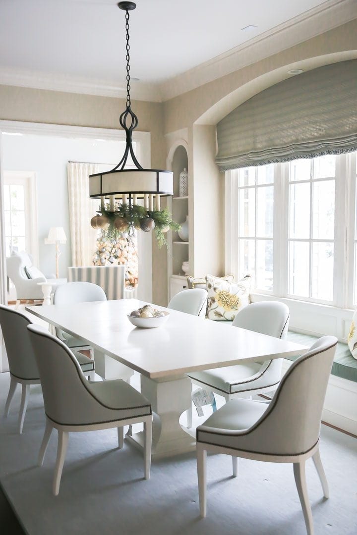 Garland in light fixture in kitchen for Christmas. Light blue upholstered chair and white pedestal kitchen table.