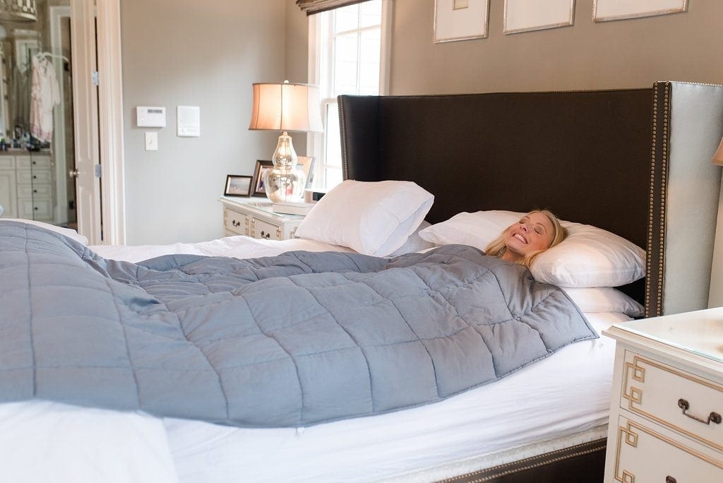 What are weighted blankets used for. Blue blanket on white bed for better sleeping.