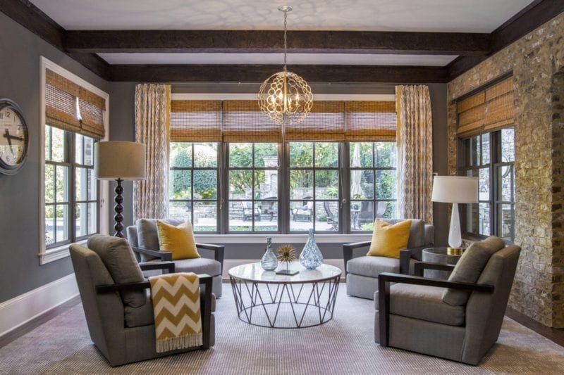 Modern basement decor. Wood beams, stone walls and Currey and Company light fixture. Gray painted walls with pops of yellow color.