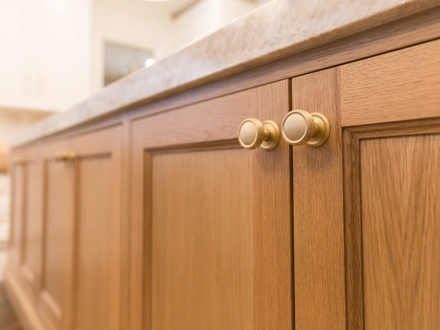 Oak Kitchen Cabinets with Taj Mahal quartz and VESTA gold hardware.