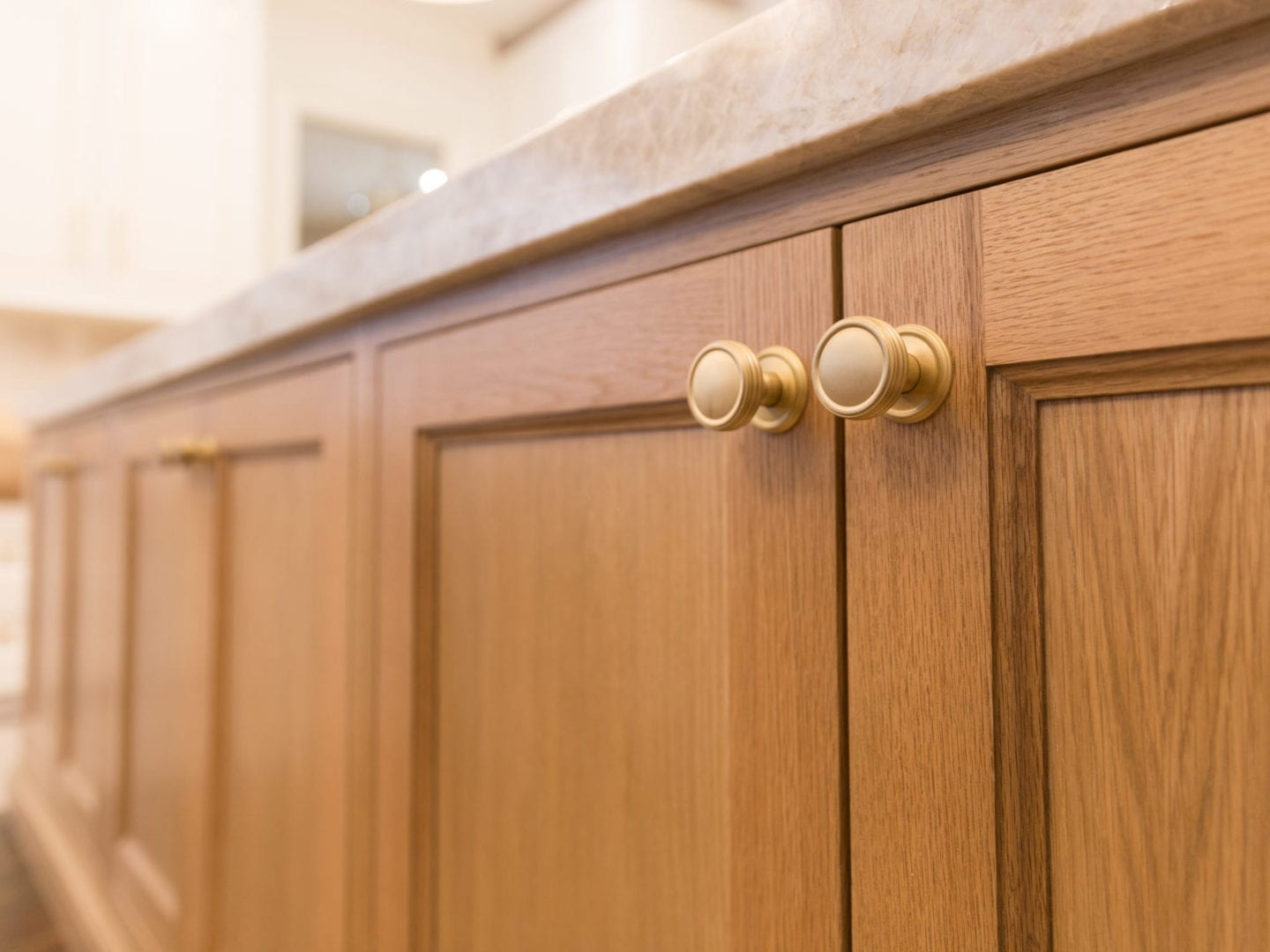 Oak Kitchen Cabinets with Taj Mahal quartz and VESTA gold hardware.