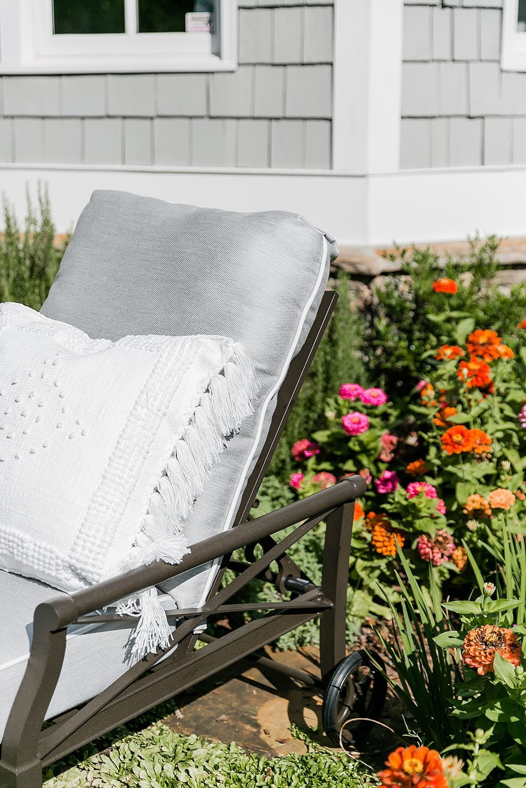 Quality outdoor furniture. Serena and Lily outdoor throw pillows with fringe and embroidery. Zinnia garden with cedar shake house in Atlanta, Georgia.