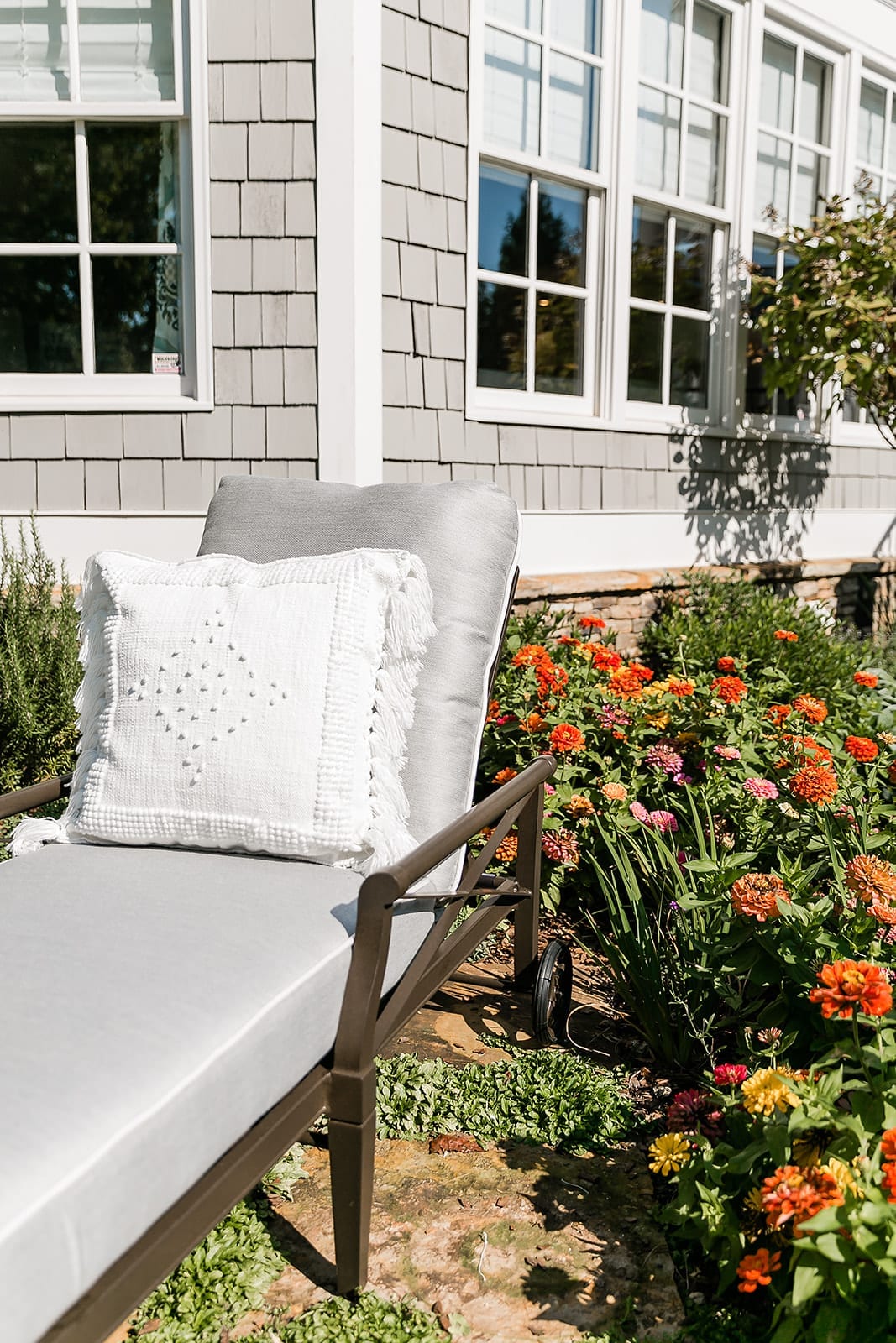 Andover Collection chaise lounge. Zinnia flower garden in Atlanta home. Oversized Chaise Lounge Chair in gray with white Serena and Lily outdoor pillow.