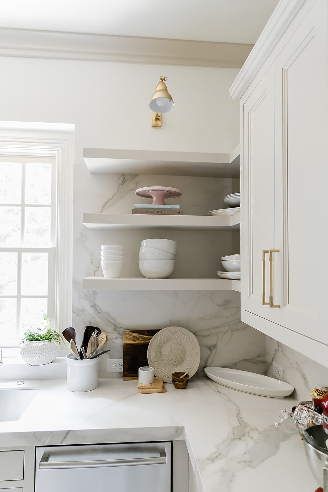 Floating Shelves in kitchen painted in Accessible beige with gold light and porcelain countertops.