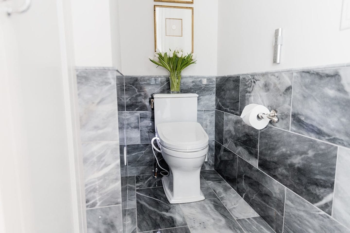 Bidet Toilets in formal master bathroom full of gray marble. White tulips and Intaglio frames.
