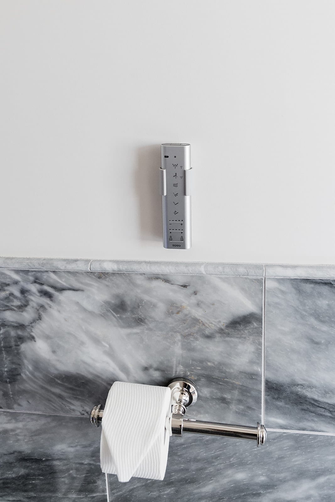 TOTO bidet toilets on top of gray marble wainscoting.