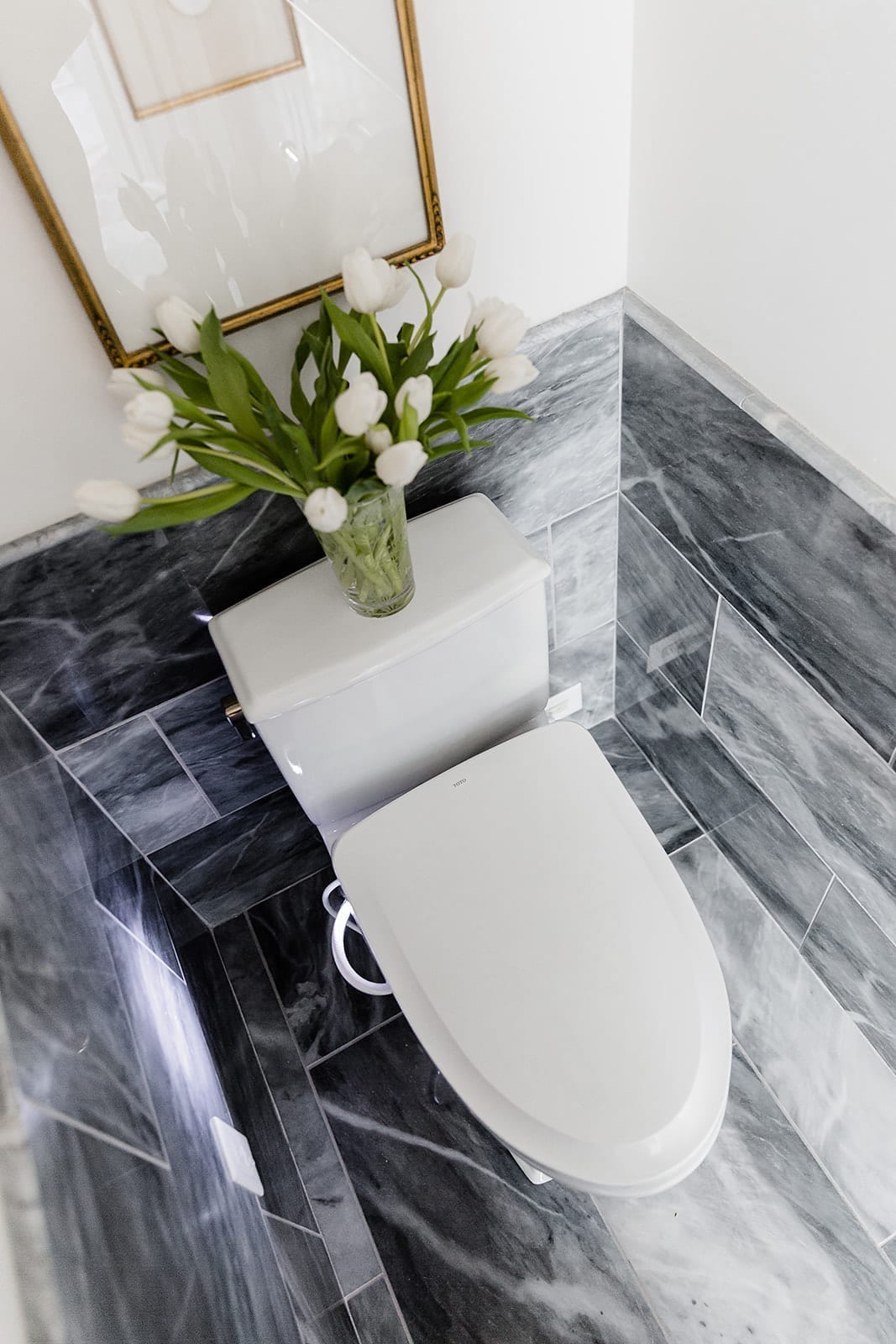 Washlet toilet with marble wainscoting and white florals.