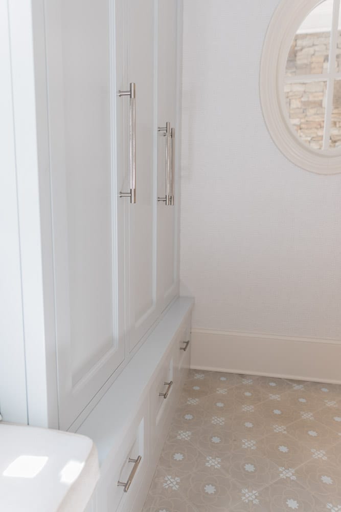 Mudroom organizing ideas. See our mudroom locker cubbies with doors, mudroom bench seat, roman shade and throw pillows all decorated with blue cabinetry, silver lantern pendant and patterned clement tile floor.