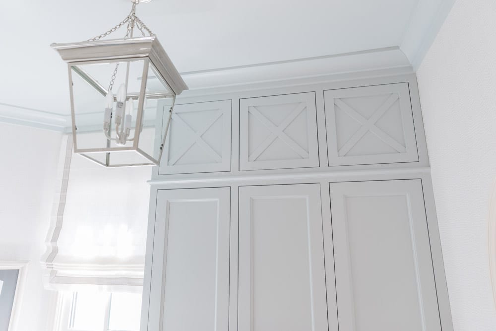 Mudroom organizing ideas. See our mudroom locker cubbies with doors, mudroom bench seat, roman shade and throw pillows all decorated with blue cabinetry, silver lantern pendant and patterned clement tile floor.