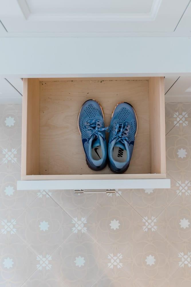 Mudroom organizing ideas. See our mudroom locker cubbies with doors, mudroom bench seat, roman shade and throw pillows all decorated with blue cabinetry, silver lantern pendant and patterned clement tile floor.