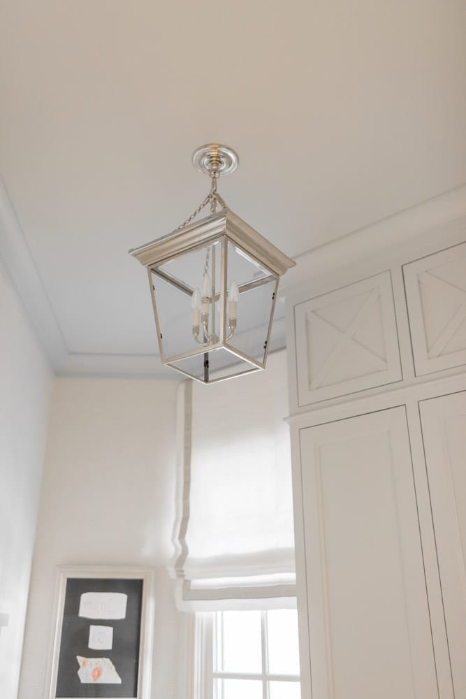 Mudroom organizing ideas. See our mudroom locker cubbies with doors, mudroom bench seat, roman shade and throw pillows all decorated with blue cabinetry, silver lantern pendant and patterned clement tile floor.