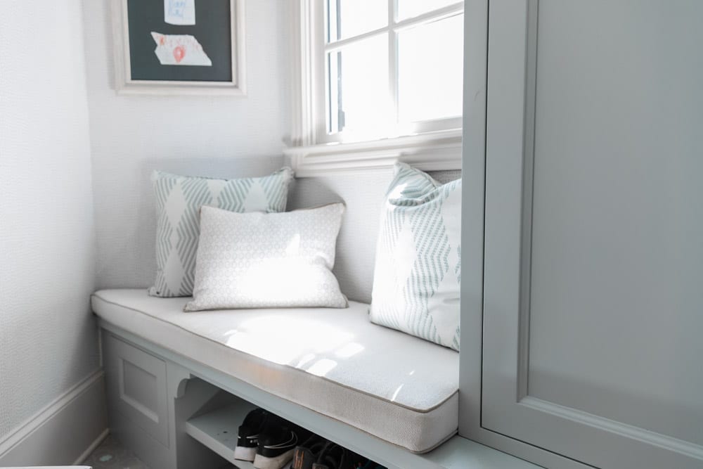 Mudroom organizing ideas. See our mudroom locker cubbies with doors, mudroom bench seat, roman shade and throw pillows all decorated with blue cabinetry, silver lantern pendant and patterned clement tile floor.