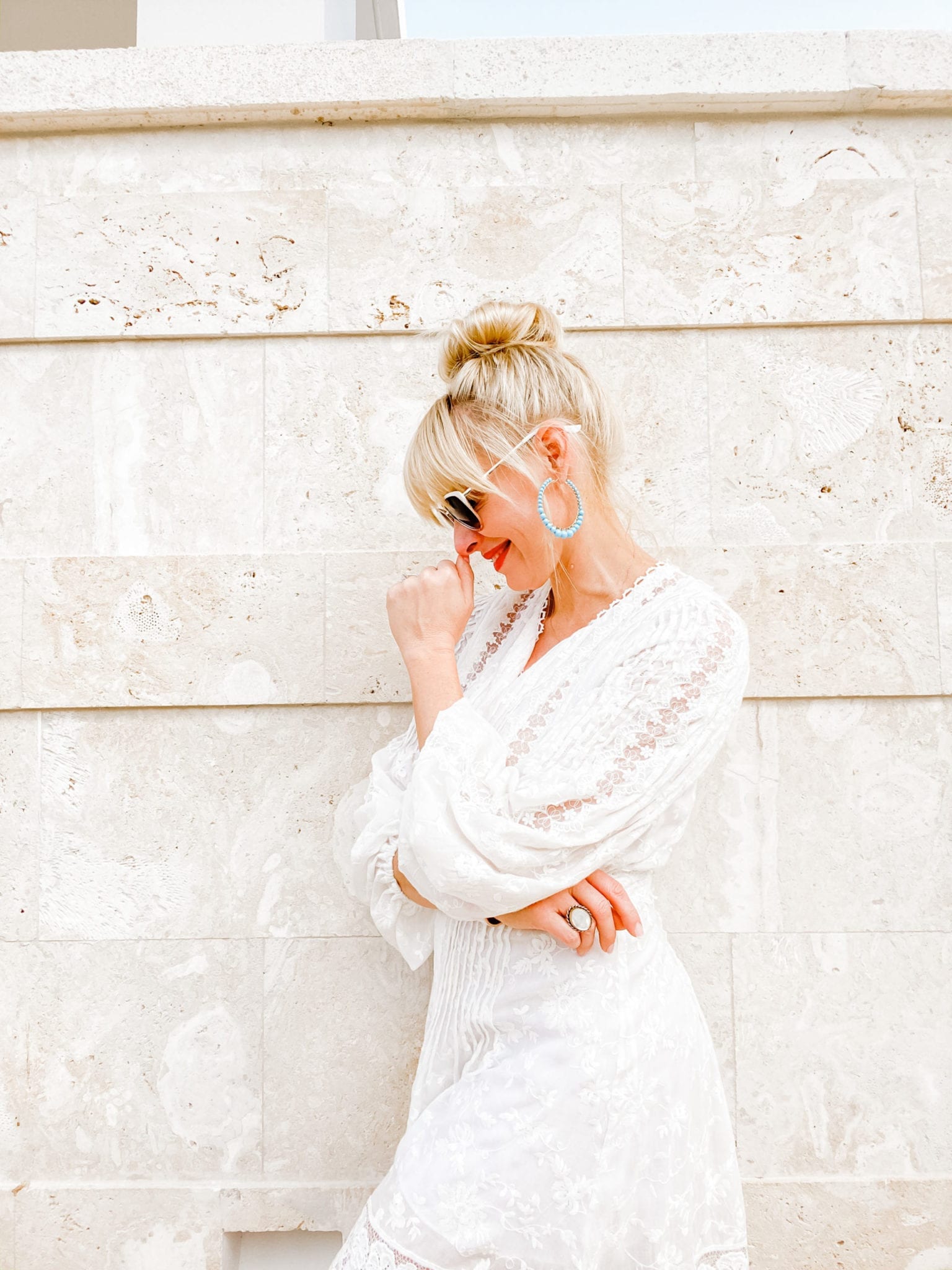 A new travel blog post from lifestyle blogger Kelly Page for blueGrayGal talking about Travel Trends 2020. Kelly poses in an Alexis white lace dresses with top knot bun.