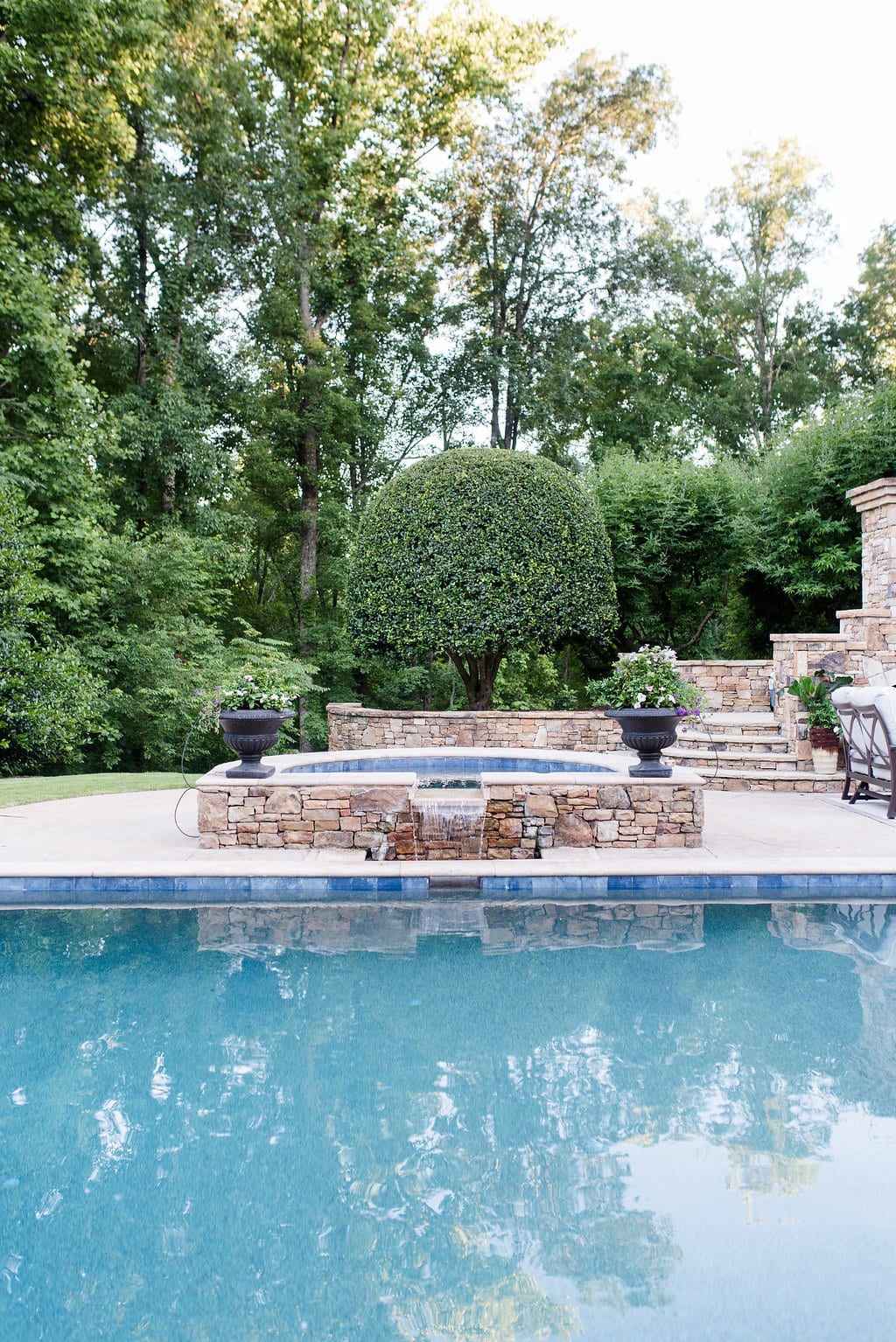 Pool design ideas include adding an elevated spa hot tub with water feature framed by two container planters.