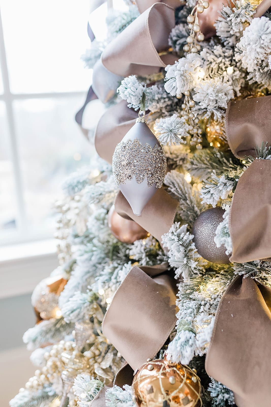 A Taupe velvet ribbon Christmas tree with blue ornaments from Frontgate collection and Frontgate tree topper. A gold Christmas skirt finishes off the taupe and navy blue accented flocked Christmas tree.