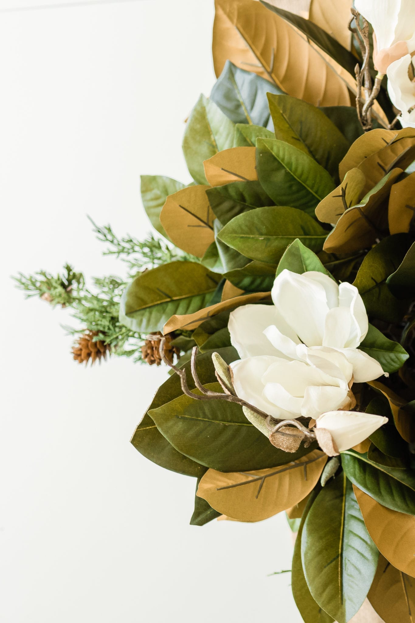 DIY silk flower fall arrangement with faux magnolia leaves and faux cedar stems for a DIY Thanksgiving table setting.