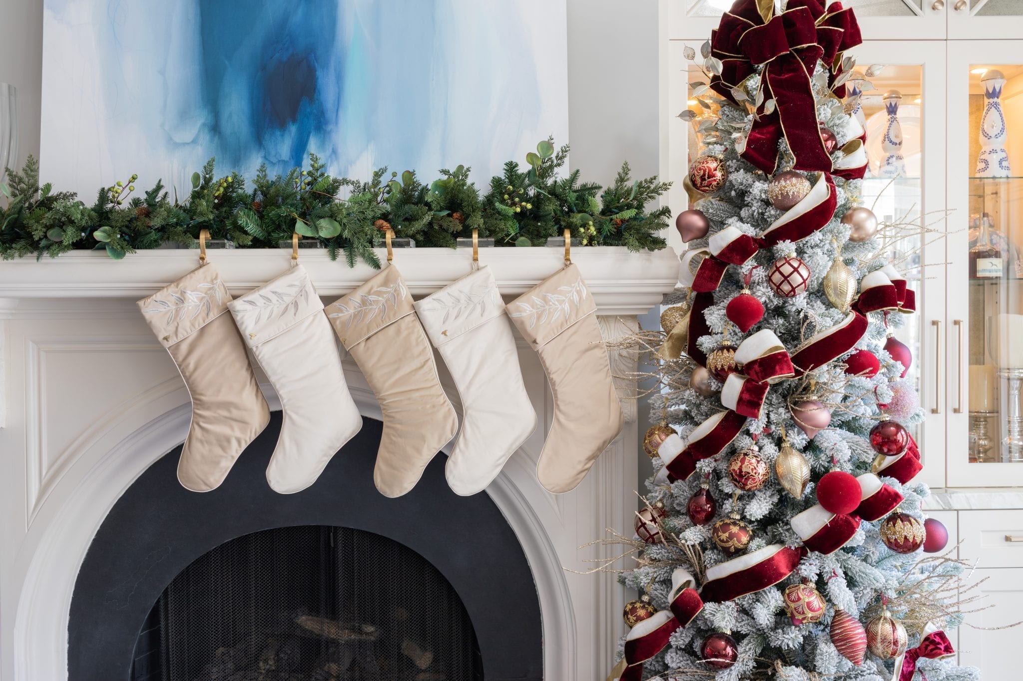 Burgundy and white Christmas Tree with silk satin stockings hung on white fireplace mantel.