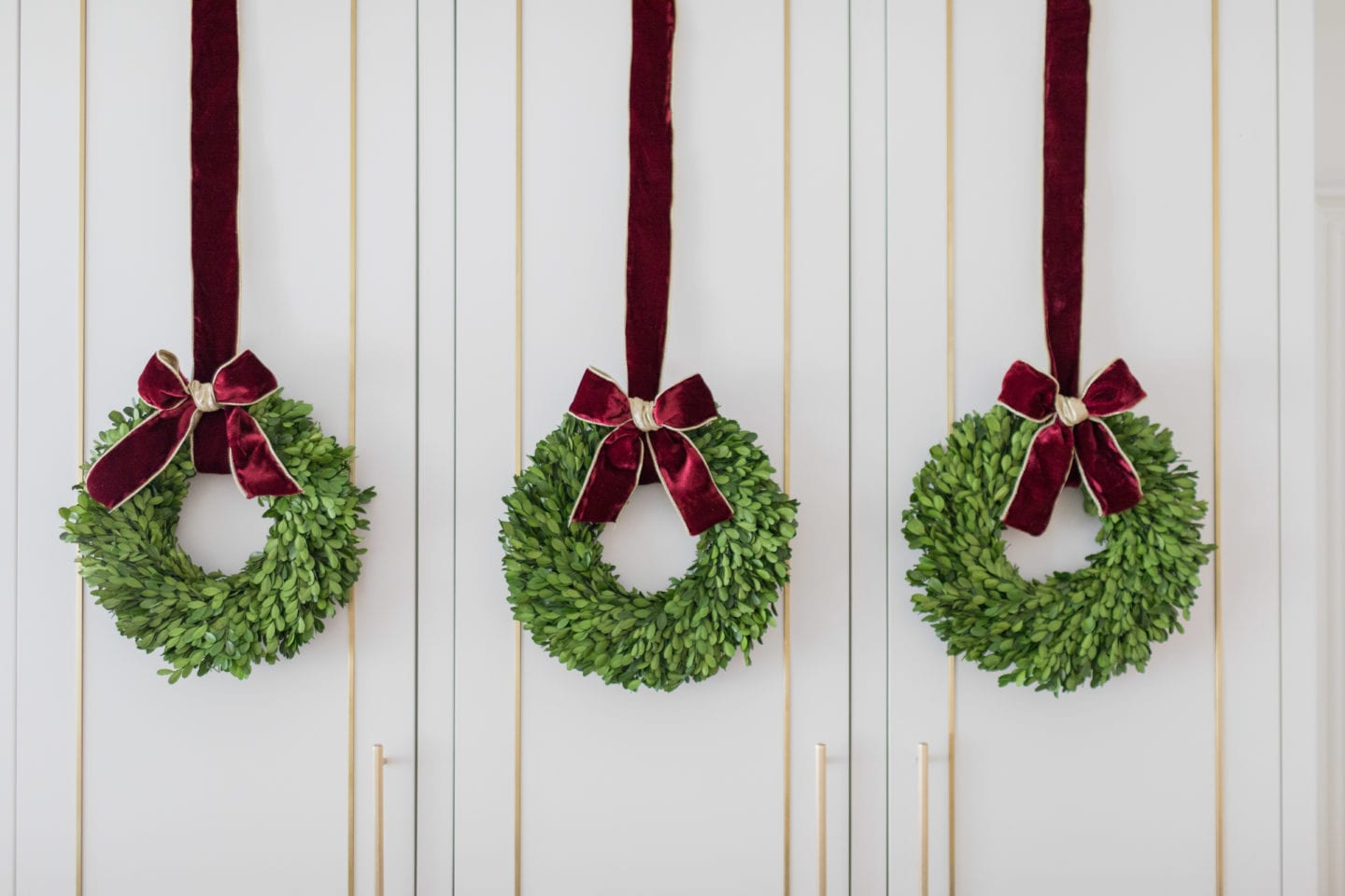 Let's face it, you can decorate for Christmas in almost every room, but where do you spend the most of your time? The kitchen! Add Christmas cabinet wreaths will bring you so much joy all Christmas long! Kitchen cabinet wreaths make a beautiful statement whether you are using mini wreaths for cabinets or one big wreath in the kitchen. Learn how to hang wreaths on kitchen cabinets without ruining them! kitchen cabinet wreaths, mini wreaths for cabinets, wreath in kitchen