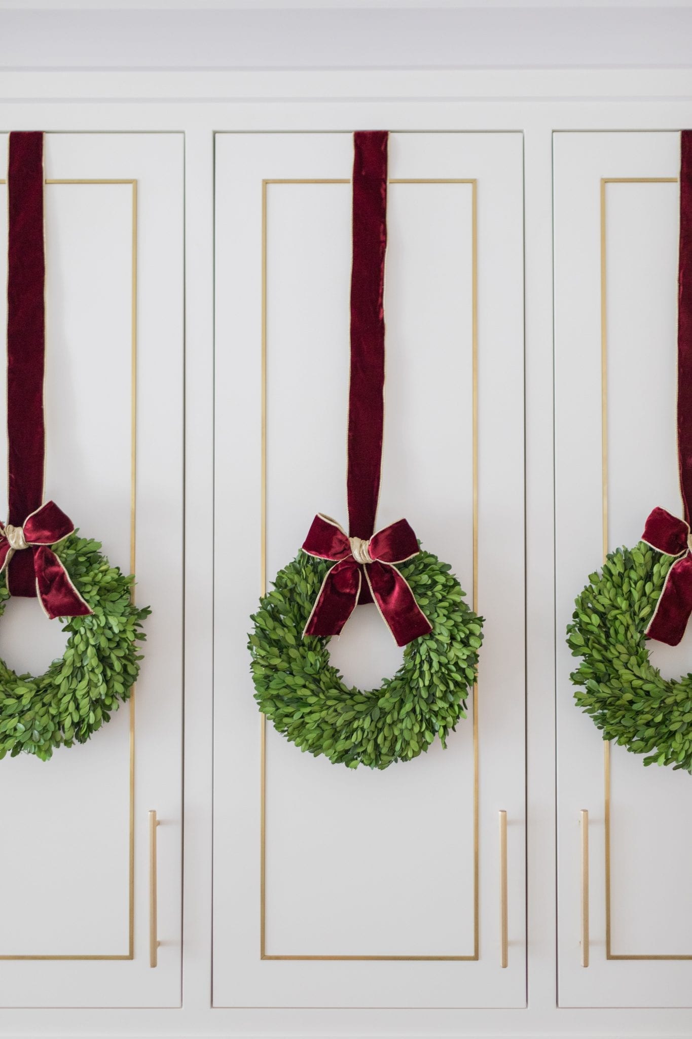 Let's face it, you can decorate for Christmas in almost every room, but where do you spend the most of your time? The kitchen! Add Christmas cabinet wreaths will bring you so much joy all Christmas long! Kitchen cabinet wreaths make a beautiful statement whether you are using mini wreaths for cabinets or one big wreath in the kitchen. Learn how to hang wreaths on kitchen cabinets without ruining them! kitchen cabinet wreaths, mini wreaths for cabinets, wreath in kitchen