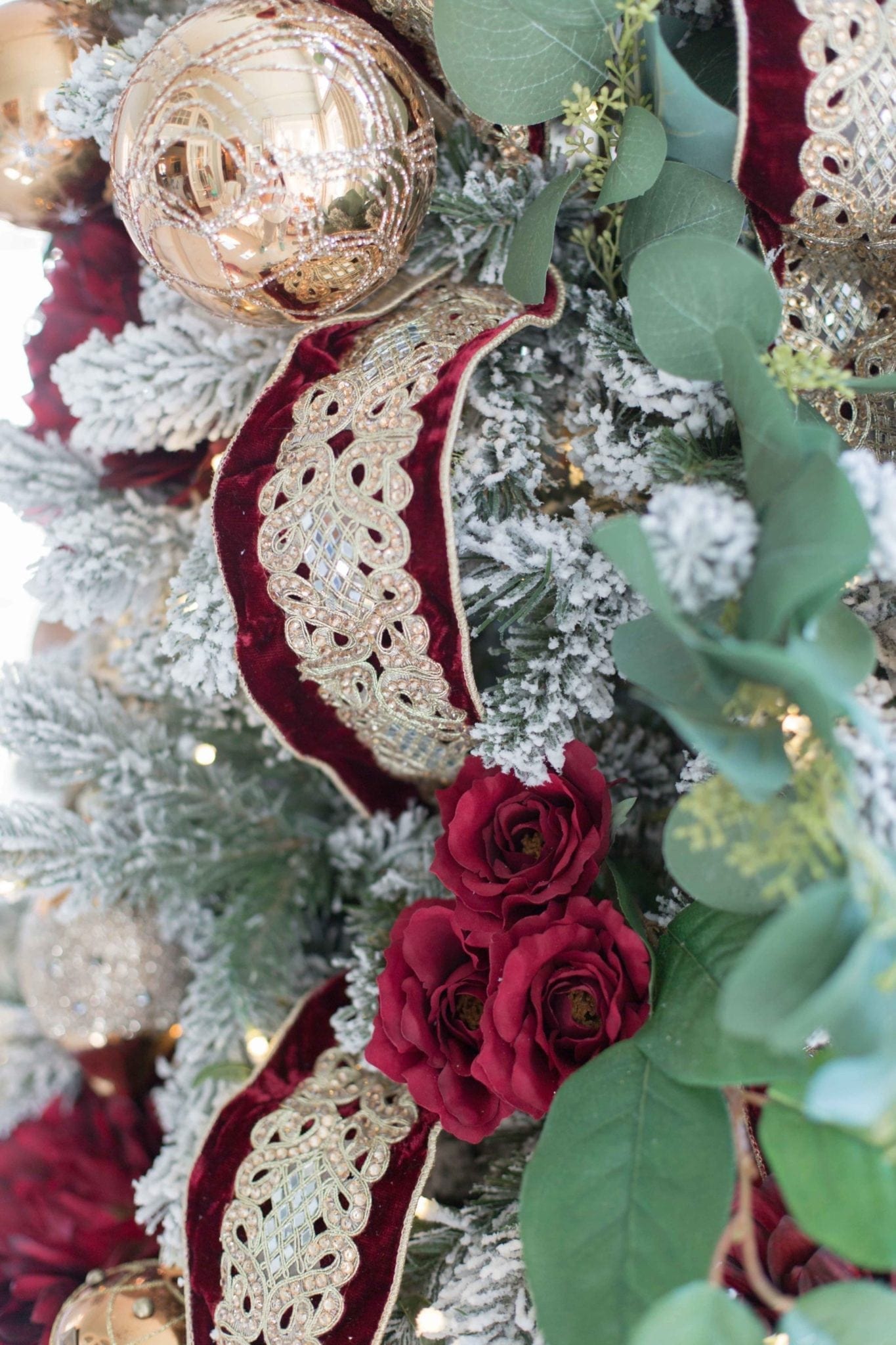 Red and Gold Christmas tree ornaments and ribbon on a King of Christmas tree with flocking.