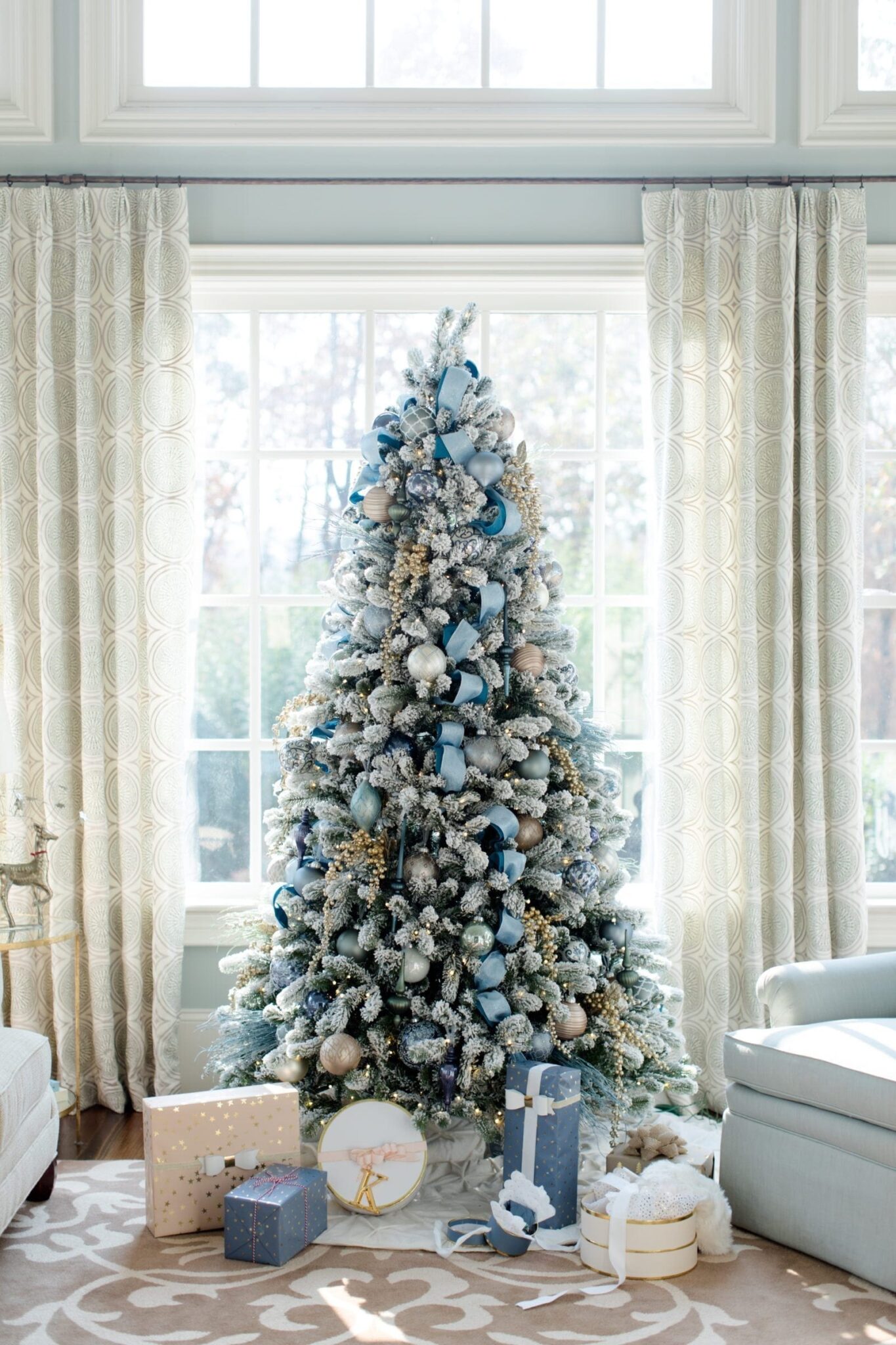 A flocked Christmas tree decorated with blue christmas ribbon by holiday blogger Kelly Page for BlueGrayGal.