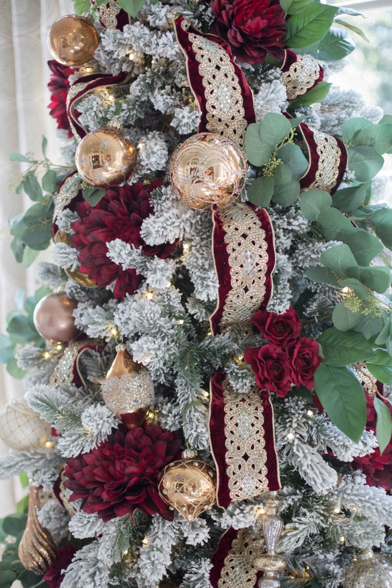 Red green and gold christmas tree decorations on a flocked Christmas tree.