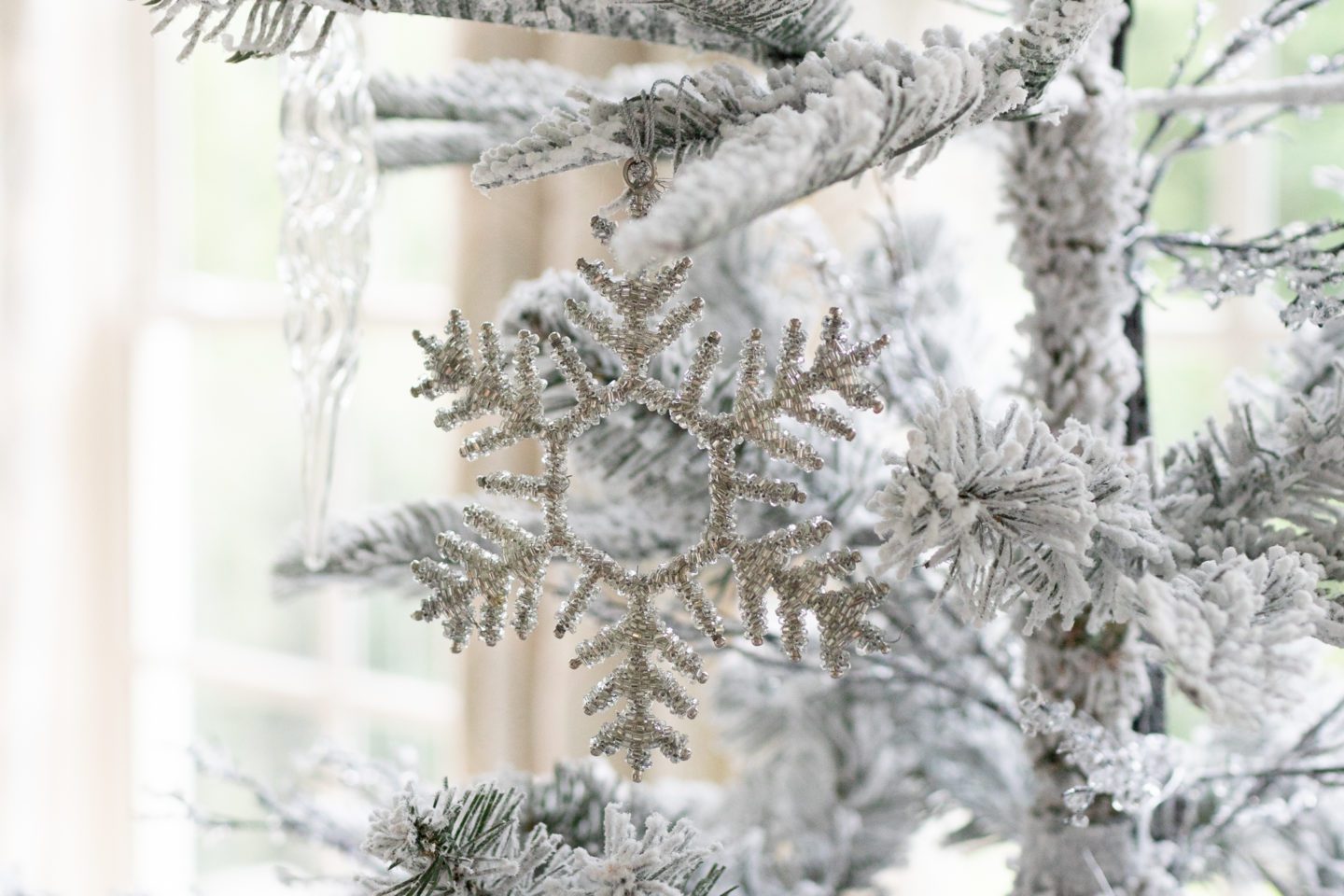 Flockd Christmas tree with winter ornaments.