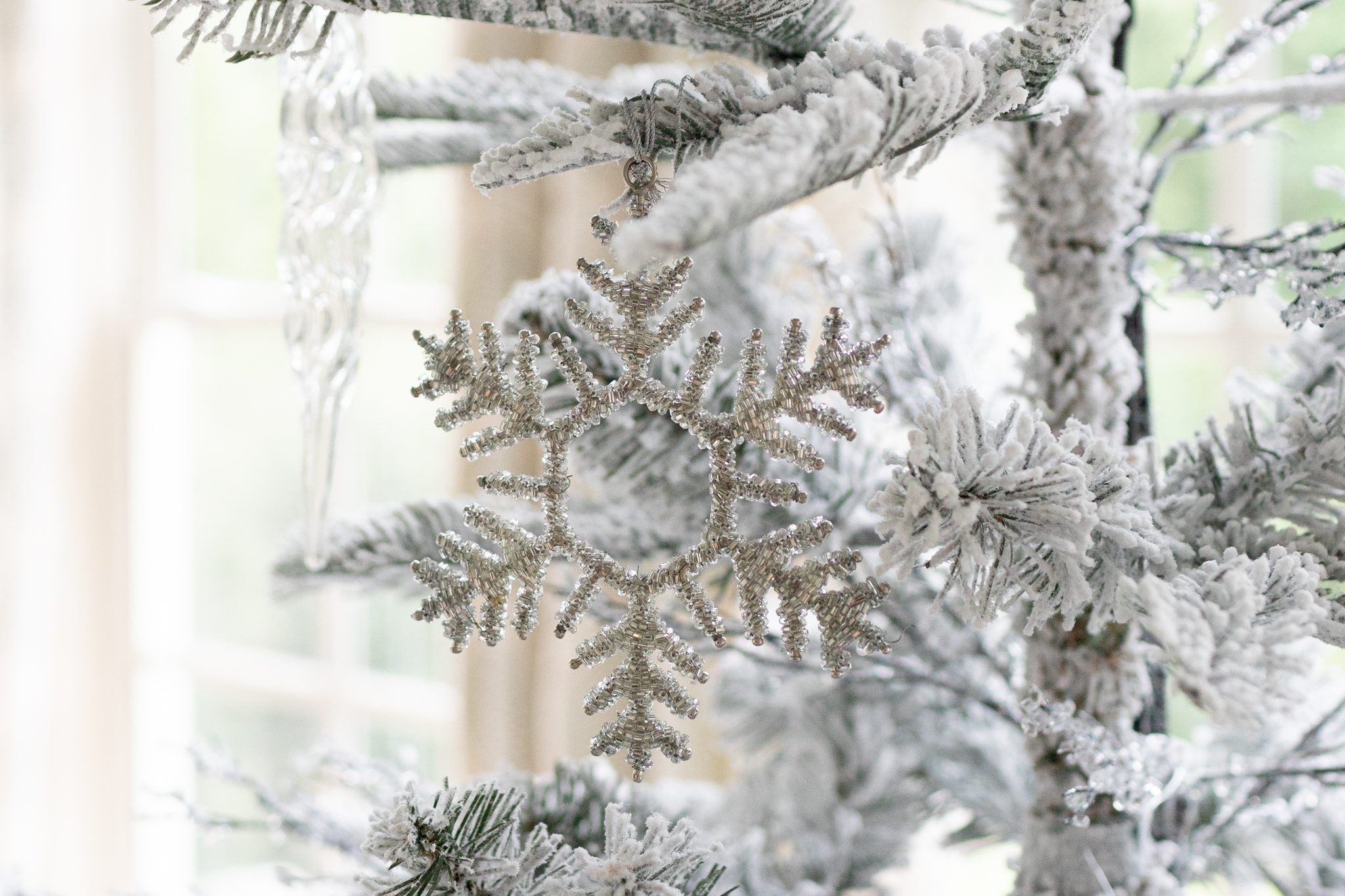 Flockd Christmas tree with winter ornaments.