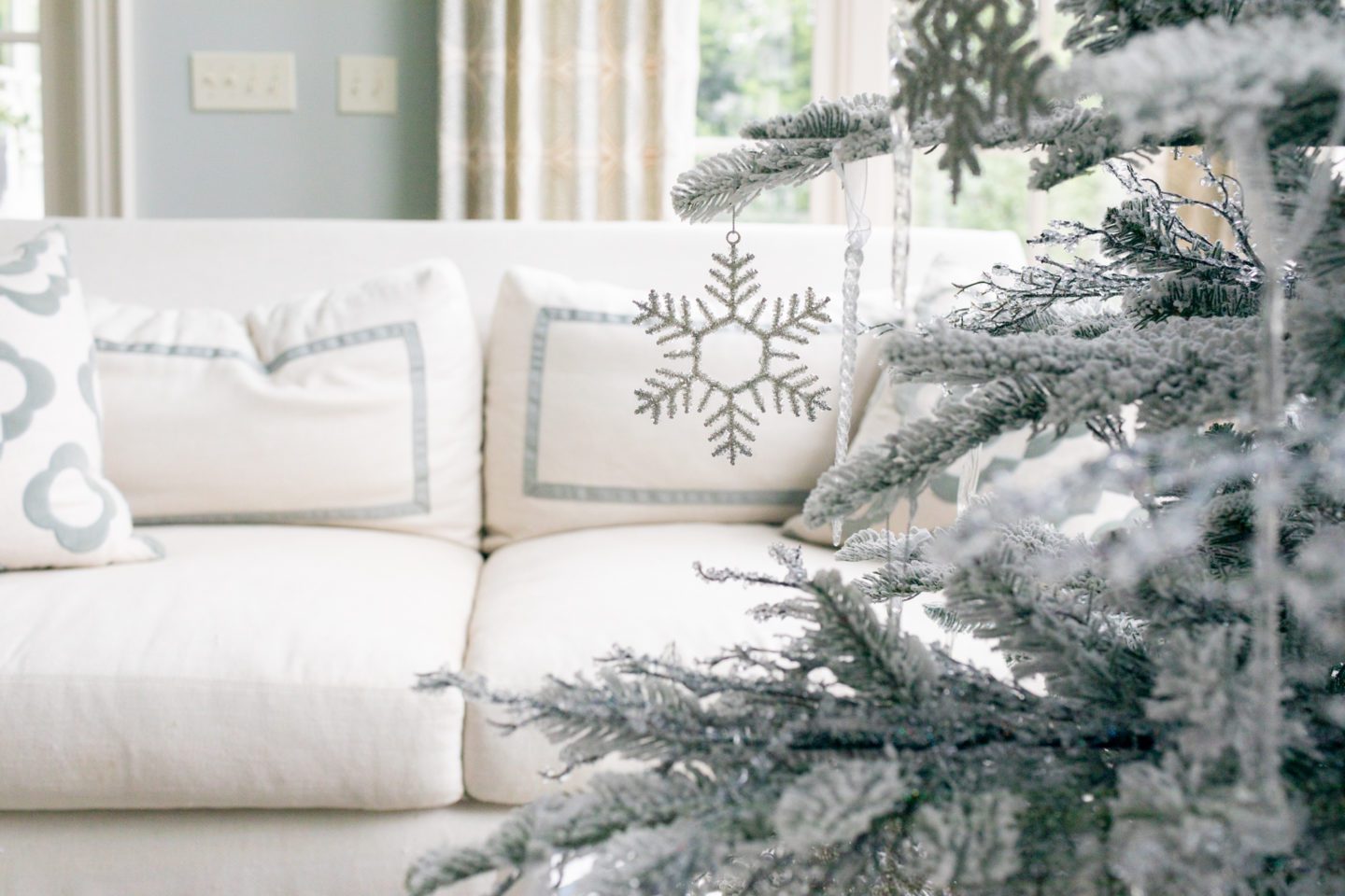 Snowflake ornament hanging on a winter white tree.