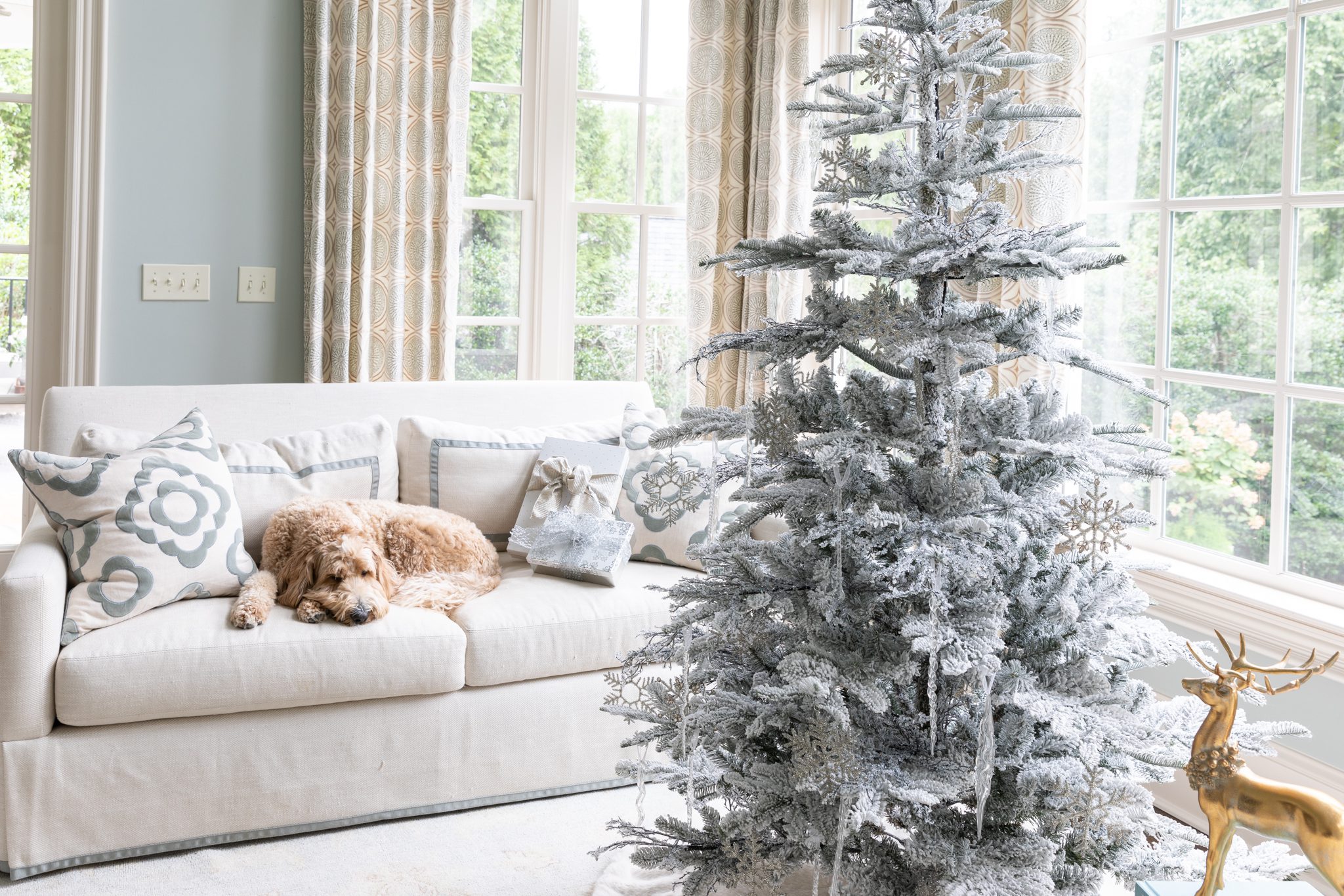 White flocked tree in a living room with a dog.
