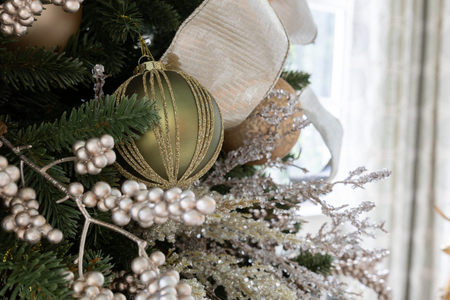 Gold sparkle picks on a green tree with gold ornaments and wired gold ribbon.