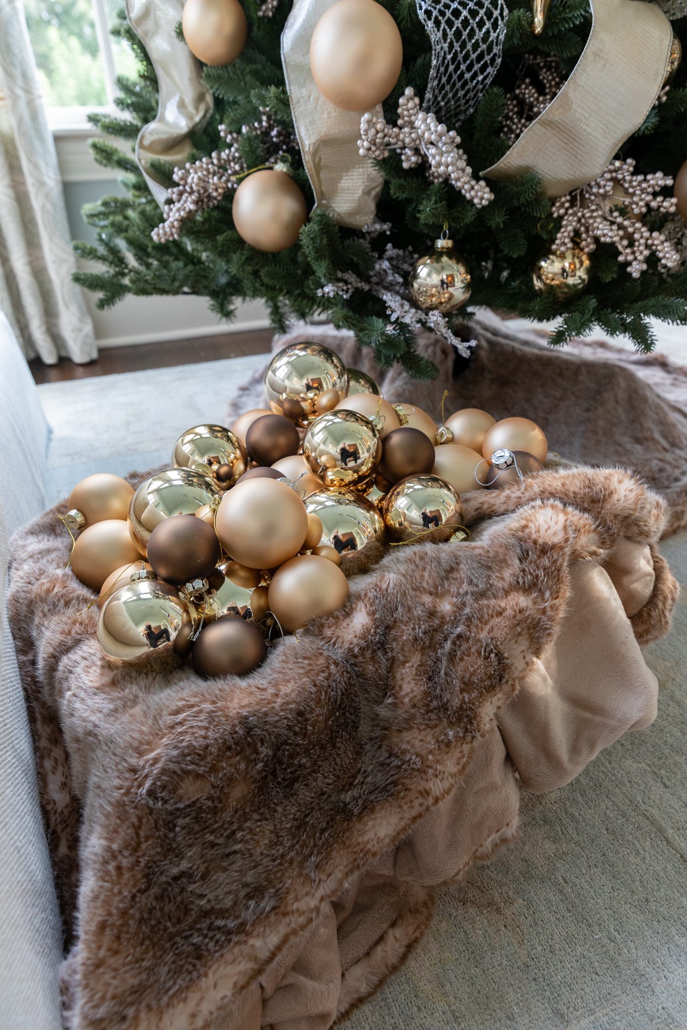 Gold ornaments on a faux fur tree skirt.