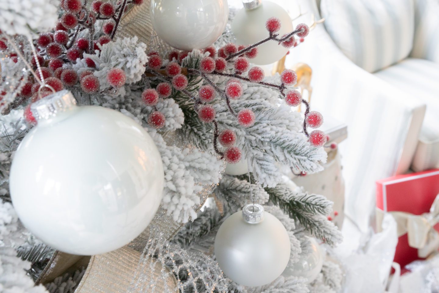 holly berry picks with white ornamnets and ribbon on a flocked Christmas tree